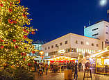 Weihnachtsmarkt mit hell erleuchtetem Weihnachtsbaum